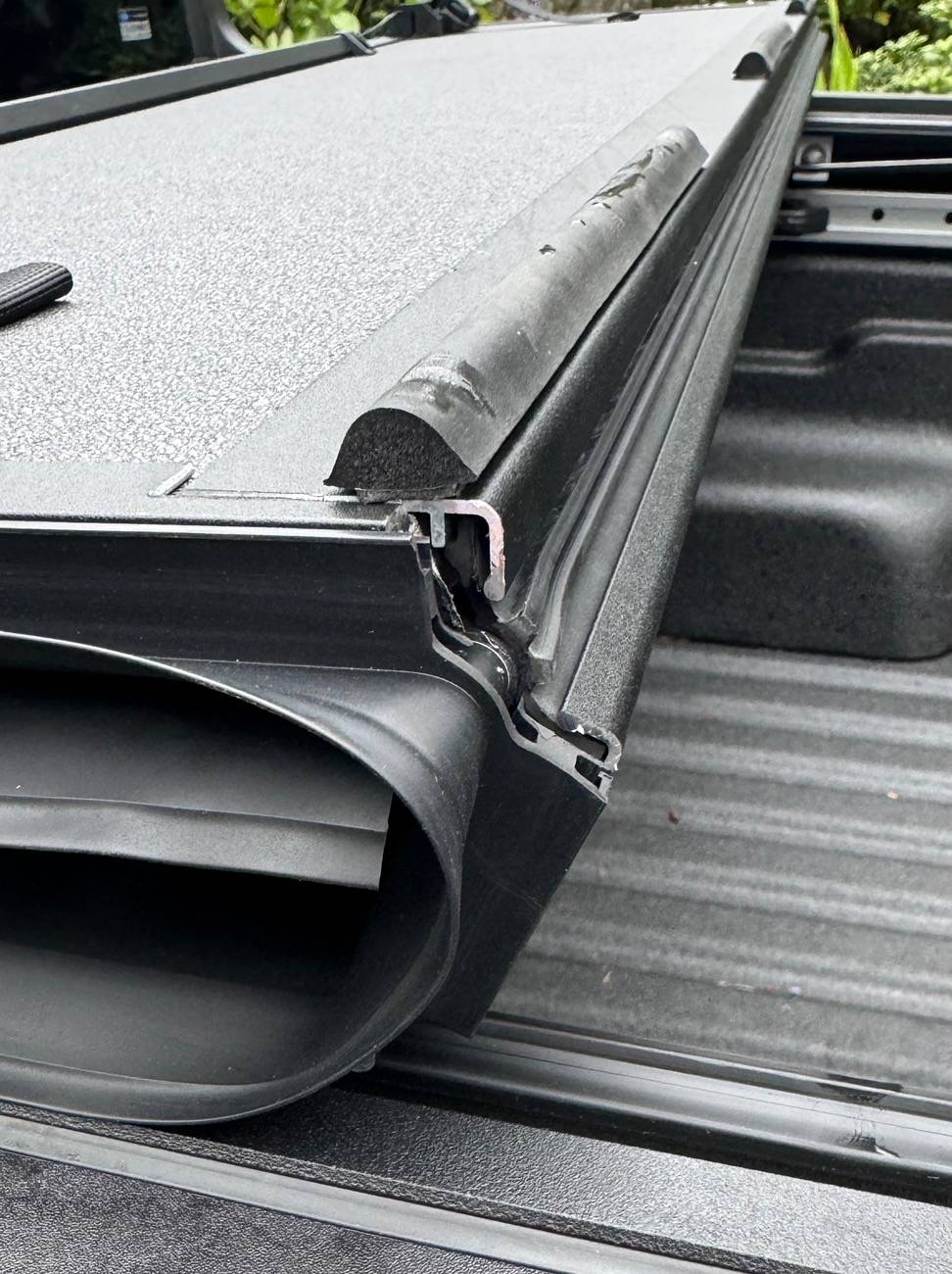 Ford Maverick Newly Ford installed tri-fold rail Tonneau bed cover with weather seal sitting way proud of the surface below, at two cover folds A_Ford_Maverick_2024_hard__tri-fold-Tonneau_bed cover_open_to_second_fold